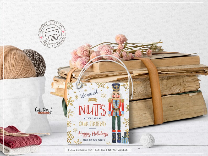 May include: A white gift tag with gold snowflakes and a red and blue illustration of a nutcracker. The text on the tag reads "We would go NUTS without you as our friend Happy Holidays from the Gail family".