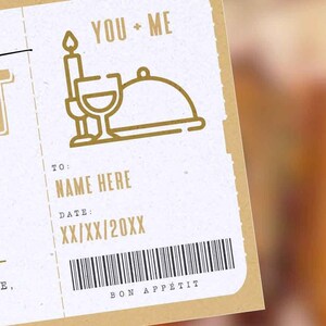 May include: A white card with gold text and icons. The card says "You + Me" and has a candle, wine glass, and plate icon. The card also says "To: Name Here", "Date: XX/XX/20XX", and "Bon App&eacute;tit".