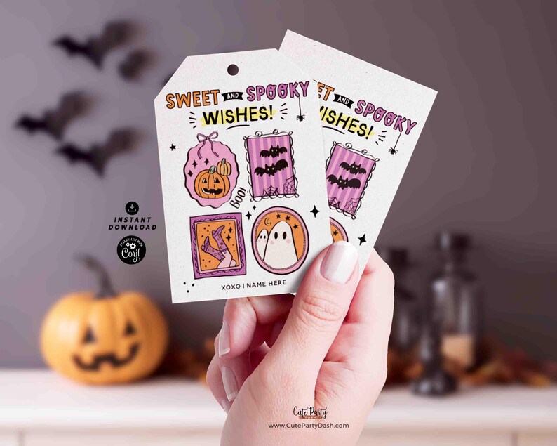 Pu&ograve; includere: Due etichette regalo a tema Halloween con la scritta "Sweet and Spooky Wishes!" e illustrazioni di zucca, pipistrelli e un fantasma. Le etichette sono tenute in mano.