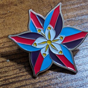 May include: A silver metal pin shaped like a flower with red, blue, white, and yellow enamel. The flower has five petals and a yellow center.