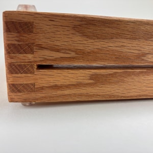 May include: Close-up of a wooden tray with a groove running along the length of the tray. The tray has a natural wood finish and is made with a dovetail joint.