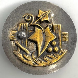 May include: A round, silver-toned button with a raised, gold-toned design. The design features a vine with leaves and berries, growing up a wooden fence with a nail.