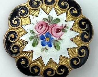 May include: A round button featuring a central white enamel inlay decorated with a painted pink rose and blue flower cluster. The border consists of alternating gold-toned metal rays and black enamel scrollwork in a scalloped edge design.