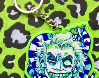 May include: A green and white striped character with a green tongue and sharp teeth, with a green and white striped snake wrapped around the character's head. The character is on a green and white keychain.