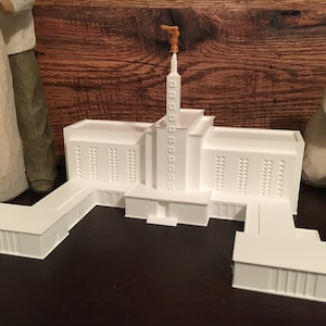 May include: A white model of a church with a tall spire and a small steeple. The model is made of plastic and has a smooth finish.