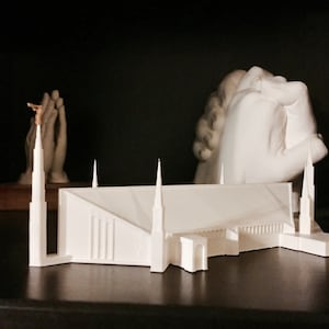 May include: White miniature model of a church with tall spires, on a black surface.