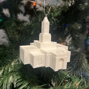 以下が含まれることがあります： クリスマスツリーに飾られた、白い3Dプリントの寺院のオーナメント