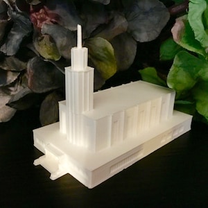 May include: A white 3D printed model of a church building with a tall spire.
