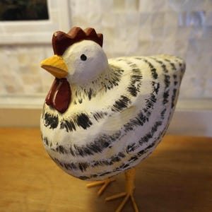 May include: A white ceramic mug with a black handle and the text "But First, Coffee" in a black, handwritten-style font. The mug is on a white surface.