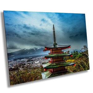May include: A traditional Japanese pagoda with red and green accents stands against a backdrop of a mountain range and a city skyline. The sky is cloudy and dramatic.