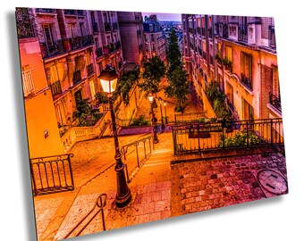 May include: A view of a narrow, cobblestone street in Paris, France. The street is lined with buildings and has a set of stairs leading up to the top. The street is lit by streetlights and the buildings are illuminated by the warm glow of the lights.
