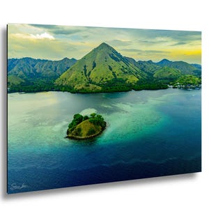 Peut inclure: Une impression murale paysagère montrant une grande montagne verte dominant une baie calme, avec une petite île herbeuse au premier plan entourée d'eaux turquoise et bleu profond sous un ciel doux, nuageux, jaune et blanc.