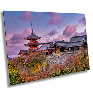 May include: A traditional Japanese pagoda with a red and orange roof stands on a hilltop overlooking a forest. The sky is a vibrant pink and purple, creating a beautiful sunset scene.