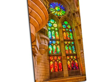 May include: A large stained glass window in a church with a colorful design of red, orange, yellow, green, blue, and purple. The window is framed by stone and has a round window above it.