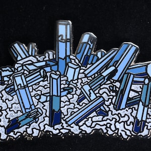 May include: A blue crystal cluster enamel pin. The pin features a cluster of blue crystals with a white background.