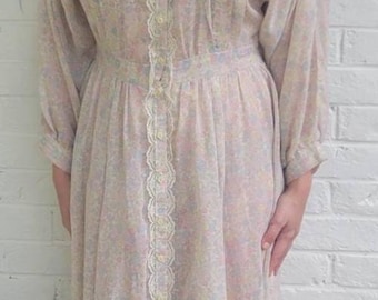 Puede incluir: Vestido vintage con estampado floral en colores pastel. El vestido presenta un cuello con ribete de encaje, una botonadura frontal y una cintura entallada. Las mangas largas y la longitud midi crean una silueta clásica y femenina.