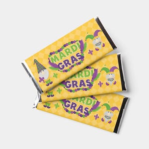 May include: Three wrapped candy bars with a yellow diamond pattern. Each bar features the words "Mardi Gras" in green and purple, along with a cartoon gnome wearing a jester hat. The bars are silver on the ends.