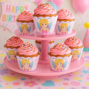 Op de afbeelding: Zes cupcakes met roze glazuur en gekleurde hagelslag, elk in een decoratieve wikkel met een illustratie van een blonde fee. De cupcakes staan op een roze kunststof etagère met twee lagen, één op de bovenste laag en vijf op de onderste.