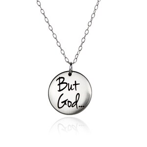 May include: A silver necklace with a round pendant that says "But God..." in black script.