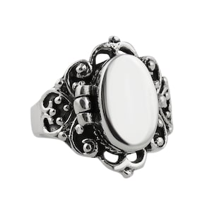 May include: A silver-toned metal ring featuring an oval-shaped locket centerpiece with a hinged cover. The band and setting are decorated with intricate, raised scrollwork and filigree patterns, creating a textured, oxidized appearance.