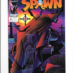 May include: A Spawn comic book issue number 2, dated June, featuring a dark, caped figure perched on a tombstone marked Simmons. The cover art displays a sunset graveyard scene with crosses, bats, and the title Spawn in large orange letters.