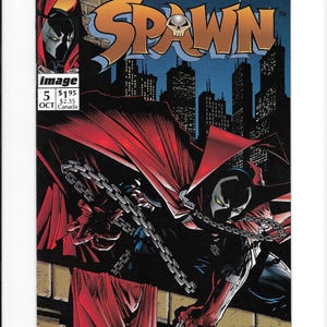 May include: A Spawn comic book issue number 5, dated October, featuring a dark city skyline background. The cover art displays the character Spawn in a black suit with a long red cape and silver chains, set against a night sky with the title Spawn.