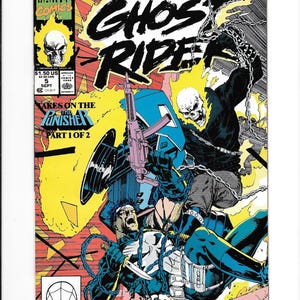 May include: A Marvel Comics Ghost Rider issue 5 comic book cover featuring a flaming skull character holding a rifle and chains, battling a character with a white skull emblem on a black chest piece, with text reading Ghost Rider and Punisher.