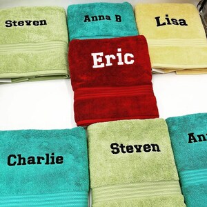 May include: A collection of six towels with embroidered names, including Steven, Anna B, Lisa, Eric, Charlie, and Steven. The towels are in various colors, including green, red, yellow, and blue.