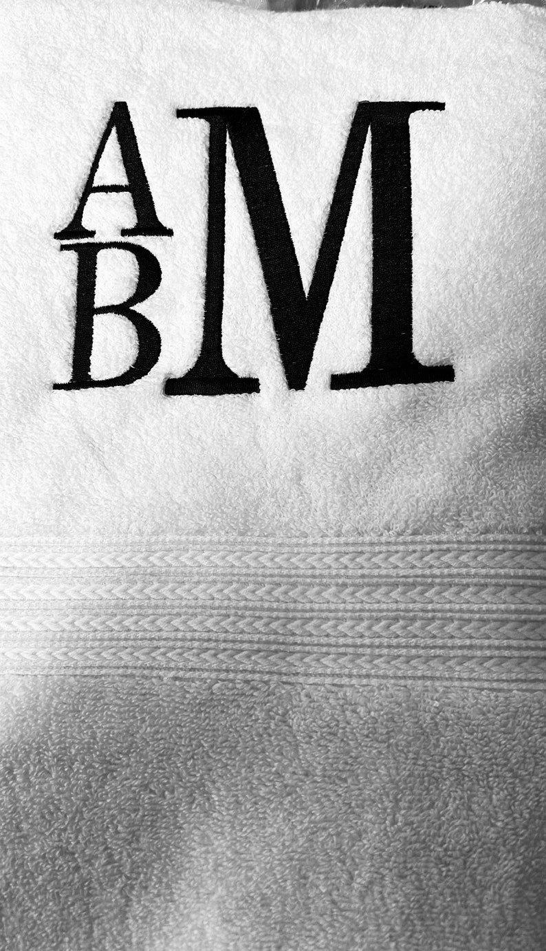 May include: White towel with black embroidered letters "A" and "M" with a smaller "B" underneath the "A".