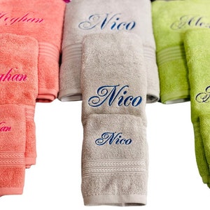 May include: Three sets of towels, one in pink, one in gray, and one in green, each with a different name embroidered on them. The names are Meghan, Nico, and Alessa.