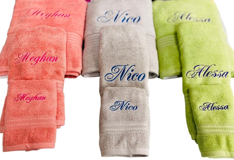 May include: Three sets of towels, one in pink, one in gray, and one in green, each with a different name embroidered on them. The names are Meghan, Nico, and Alessa.