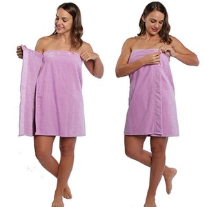 May include: A light purple spa towel wrap with button closures. The wrap is shown being worn by a person in two different poses. The towel appears soft and absorbent, ideal for use after a shower or at a spa.