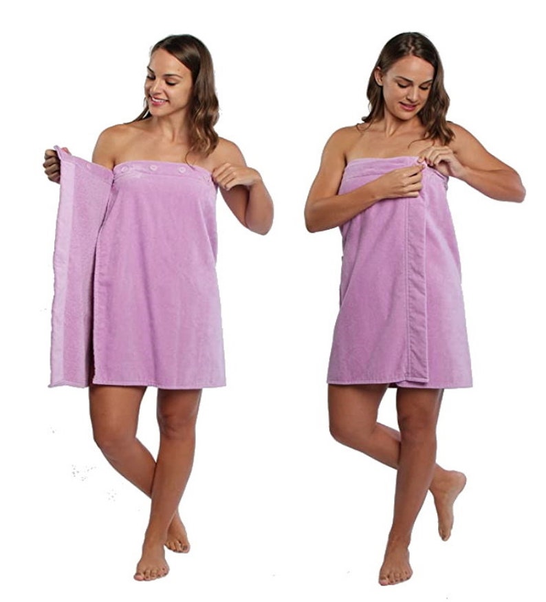 May include: A light purple spa towel wrap with button closures. The wrap is shown being worn by a person in two different poses. The towel appears soft and absorbent, ideal for use after a shower or at a spa.