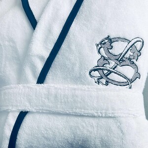 May include: White bathrobe with a navy blue trim and a black embroidered logo on the right side.