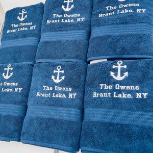 May include: Six blue bath towels with white embroidered anchors and the text "The Owens Brant Lake, NY".
