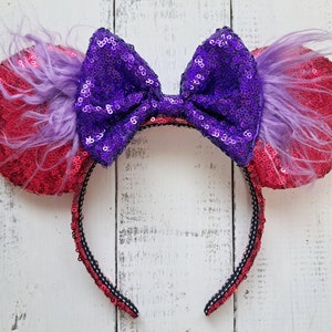 May include: Pink and purple sequined Minnie Mouse ears with a purple bow and a purple feather trim.