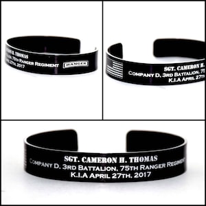 May include: Black metal bracelet with a white inscription that reads "SGT. CAMERON H. THOMAS COMPANY D. 3RD BATTALION. 75TH RANGER REGIMENT K.I.A APRIL 27TH, 2017".