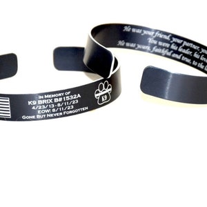 May include: Black metal bracelet with an American flag, the text "IN MEMORY OF K9 BRIX B#1532A 4/23/13-8/11/23 EOW: 8/11/23 GONE BUT NEVER FORGOTTEN" and a paw print with the text "K9".
