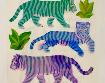May include: Three colorful tiger stickers with a green leaf sticker. The tigers are blue, purple, and green with black stripes.