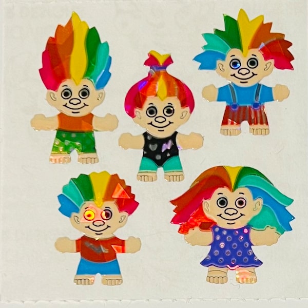 Può includere: Cinque adesivi di troll colorati con capelli arcobaleno e abiti diversi. Gli adesivi sono su uno sfondo bianco.