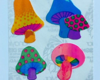 May include: Four colorful mushroom stickers with polka dots and rainbow designs. The stickers are on a white background with a pattern.