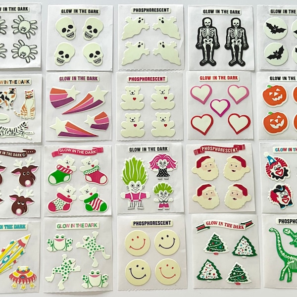 Può includere: Un foglio di adesivi che brillano al buio e fosforescenti con vari disegni, tra cui un teschio, un fantasma, uno scheletro, un pipistrello, un gatto, una stella, un cuore, una zucca, una renna, un pupazzo di neve, un troll, un clown, una rana, un'emoticon sorridente, un albero di Natale e un dinosauro.