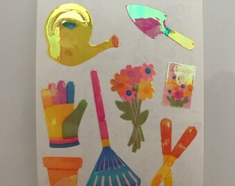May include: A set of colorful gardening stickers featuring a watering can, rake, trowel, gloves, flower bouquet, and a pair of scissors.