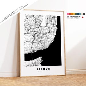 May include: A black and white map print of Lisbon, Portugal. The map shows the city's streets and coastline. The city name "Lisbon" is printed in white at the bottom of the map.
