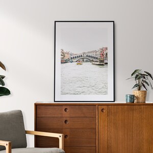 Puede incluir: Una fotograf&iacute;a enmarcada en negro de un puente sobre un canal en Venecia, Italia. El puente es de piedra y tiene varios arcos. Hay barcos en el canal y edificios a ambos lados del canal.