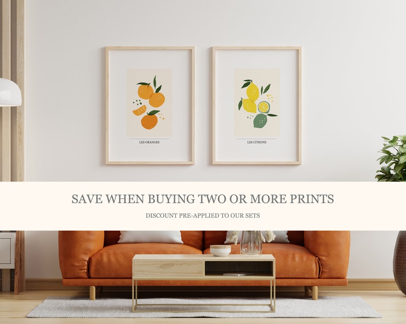 May include: Two framed prints with illustrations of oranges and lemons. The prints are on a white background with the text "Les Oranges" and "Les Citrons" below the illustrations. The text "SAVE WHEN BUYING TWO OR MORE PRINTS" is displayed in a white banner below the prints. The text "DISCOUNT PRE-APPLIED TO OUR SETS" is displayed below the banner.