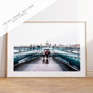 Può includere: Una vista del Millennium Bridge a Londra, in Inghilterra, con la Cattedrale di San Paolo sullo sfondo. Le persone camminano sul ponte e lo skyline della città è visibile in lontananza.