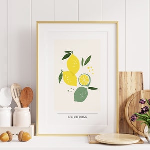 May include: A framed print with a gold frame and a white mat. The print features a stylized illustration of lemons and limes with green leaves and the text "Les Citrons".