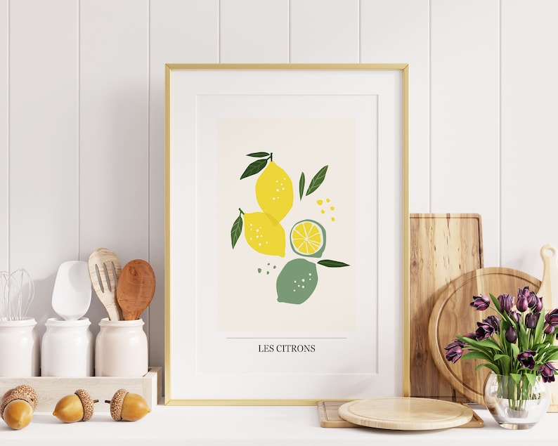 May include: A framed print with a gold frame and a white mat. The print features a stylized illustration of lemons and limes with green leaves and the text "Les Citrons".