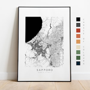May include: Black and white city map print of Sapporo, Japan. The map shows the city's streets and waterways. The print is framed in a black frame and has a white background. The text "SAPPORO" is printed below the map.